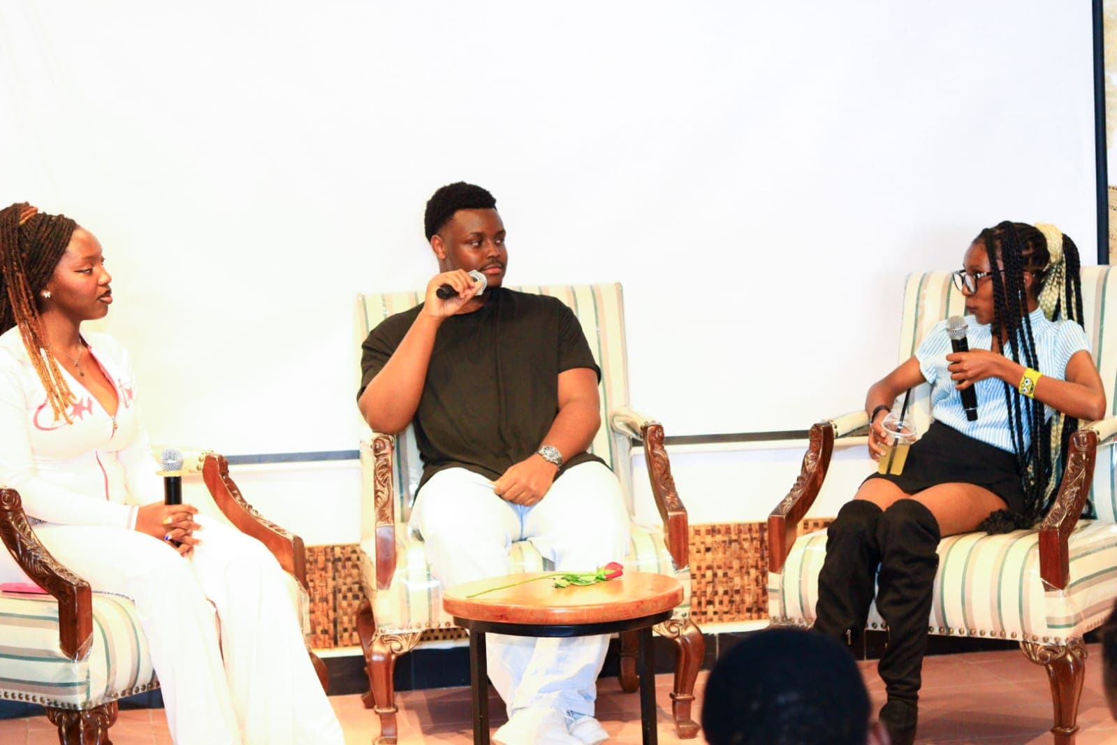 Three speakers seated in armchairs on a lit stage during a panel discussion