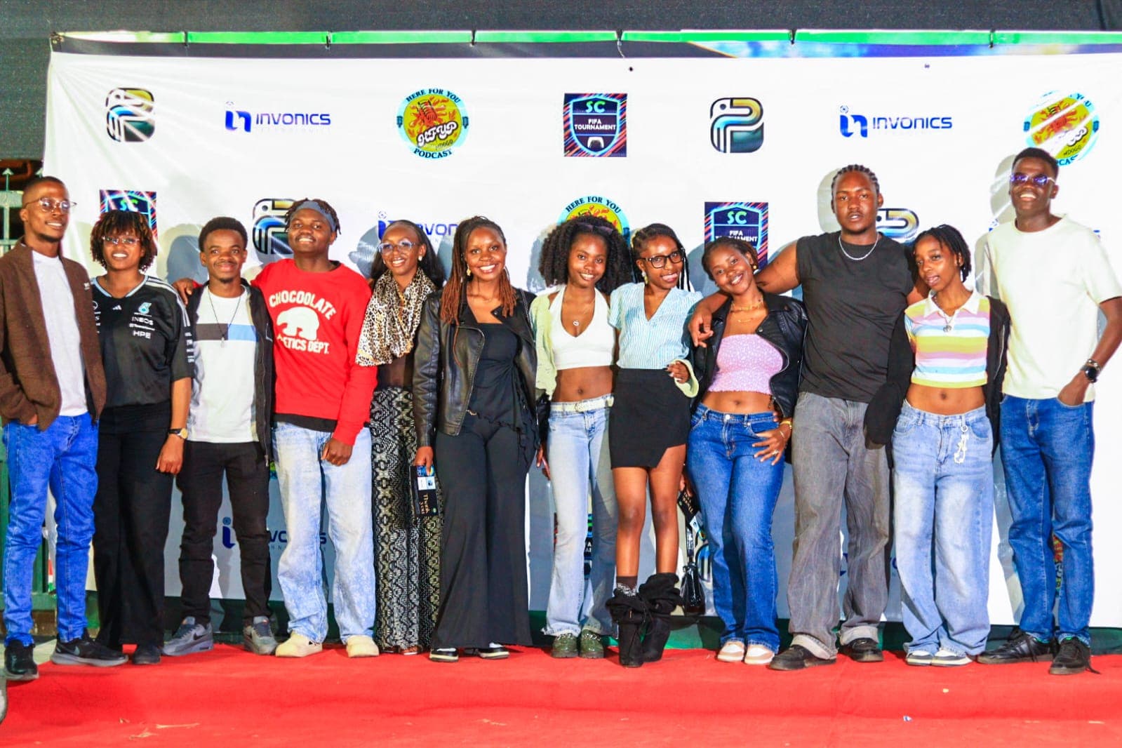 Attendees standing together on a red carpet under a colourful branded backdrop